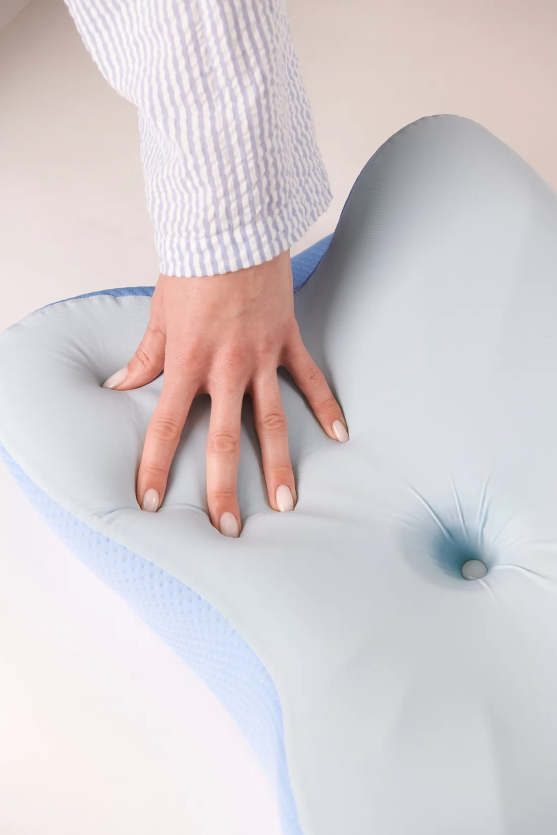 A hand resting naturally in the wing of the contoured pillow
